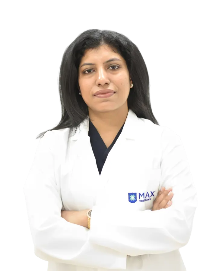 gynecologist and Obstetrician in gomti nagar, lucknow, Dr. Bhumika Bansal standing in a white lab coat with the 'Max Healthcare' logo and arms crossed against a red backdrop.